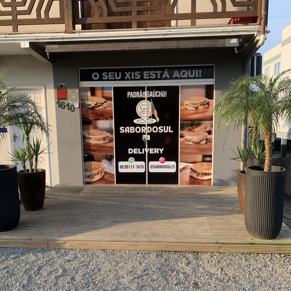 A frente do Sabor do Sul, com a placa de delivery na porta de vidro